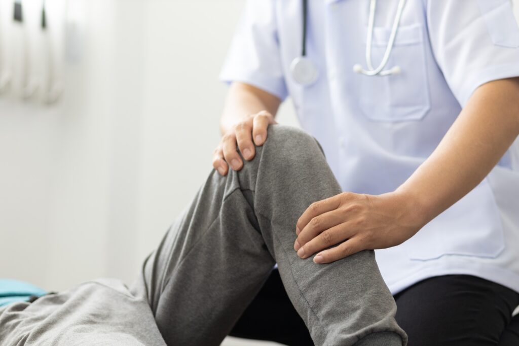 The doctor performs physical therapy on the patient's knee in the medical examination room.